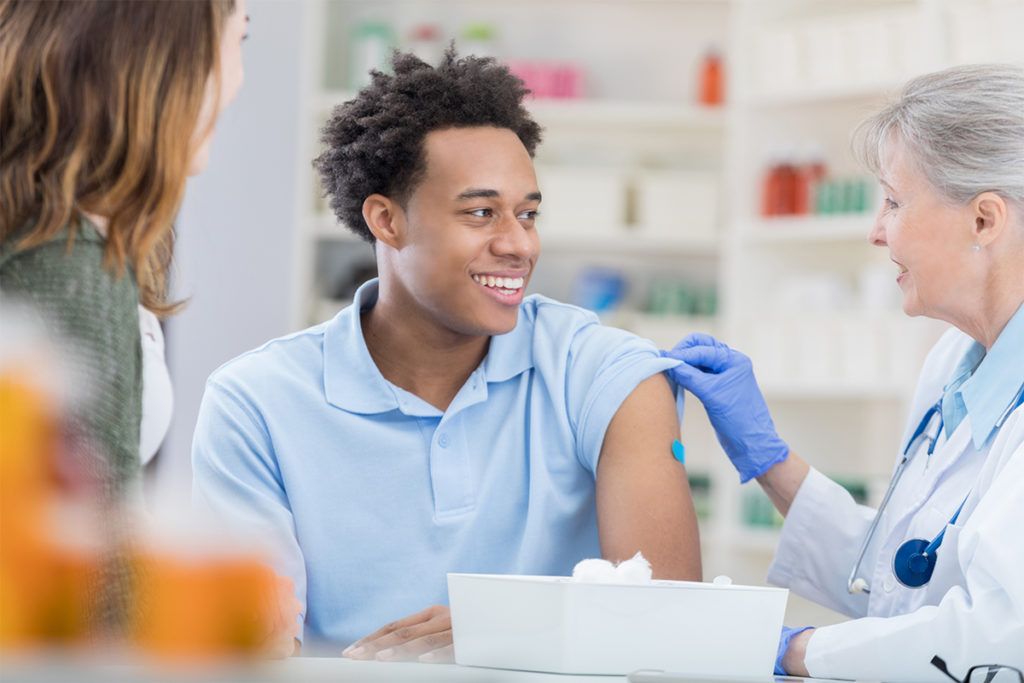 Young man smiles in relief at pharmacist after flu vaccination